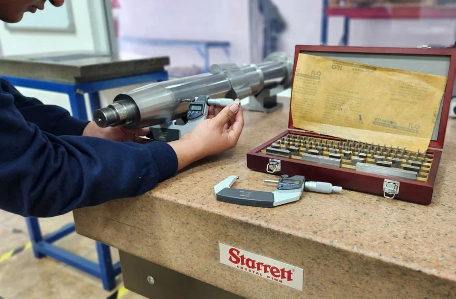 Medición de micras en eje de husillo con micrómetro digital de alta precisión.