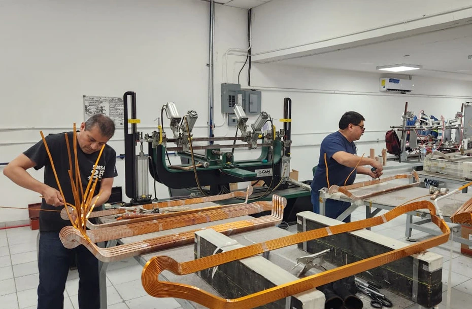 Técnicos especializados fabricando bobinas de cobre preformadas con aislamiento de alta calidad para motores de media y alta tensión.
