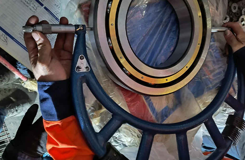 Uso de micrómetro de alta precisión para la verificación de medidas y tolerancias en un rodamiento industrial de gran tamaño.