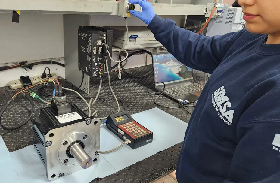 Ingeniera configurando parámetros de un servodrive mediante software especializado y consola manual.