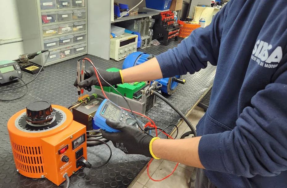 Técnico realizando pruebas de voltaje con multímetro y variac a un equipo de control industrial.