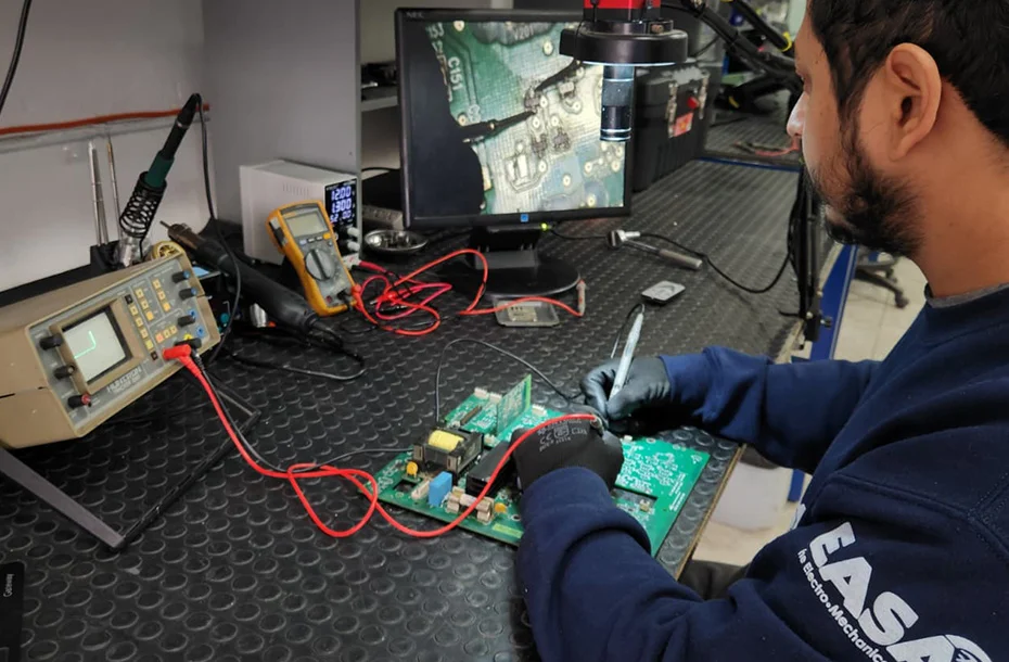 Reparación de tarjetas electrónicas industriales para servomotores bajo microscopio.